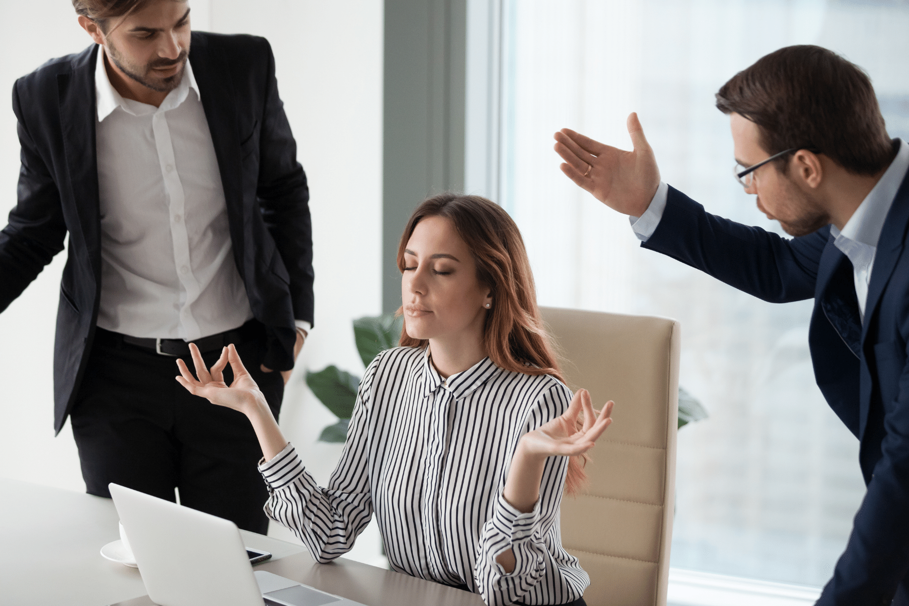 a woman practicing peace while two men at work are arguing about her head