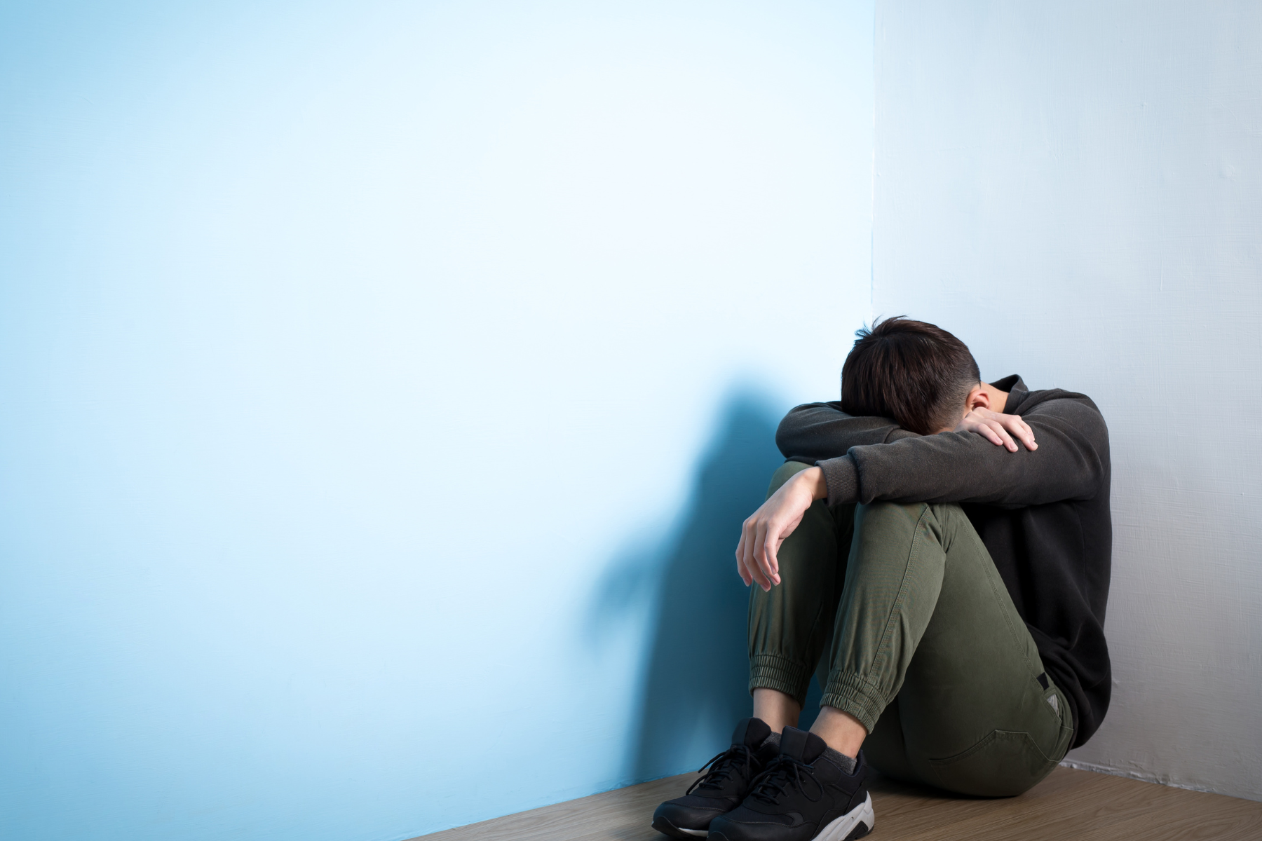 Man sitting on the floor with his head in his hands